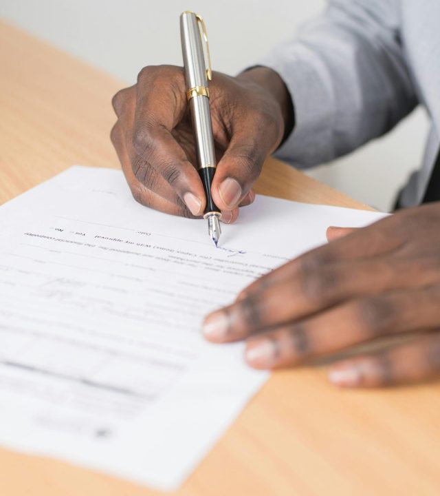 Close-up of a businessman signing a contract at an office desk.